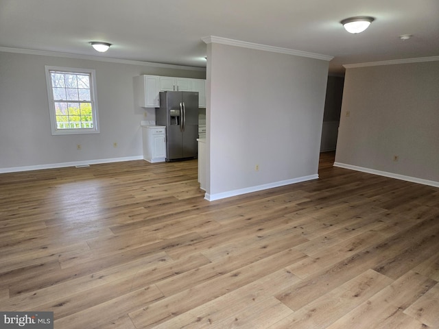 unfurnished living room with crown molding, baseboards, and light wood-type flooring