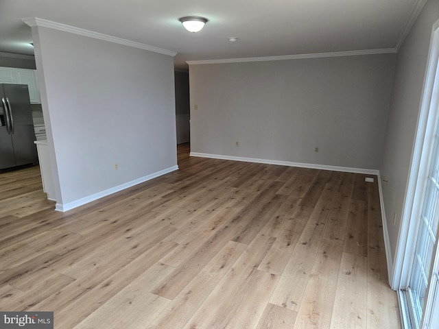 spare room with light wood-style floors, crown molding, and baseboards