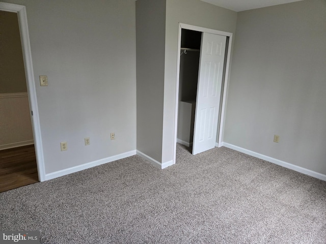 unfurnished bedroom featuring carpet floors, baseboards, and a closet