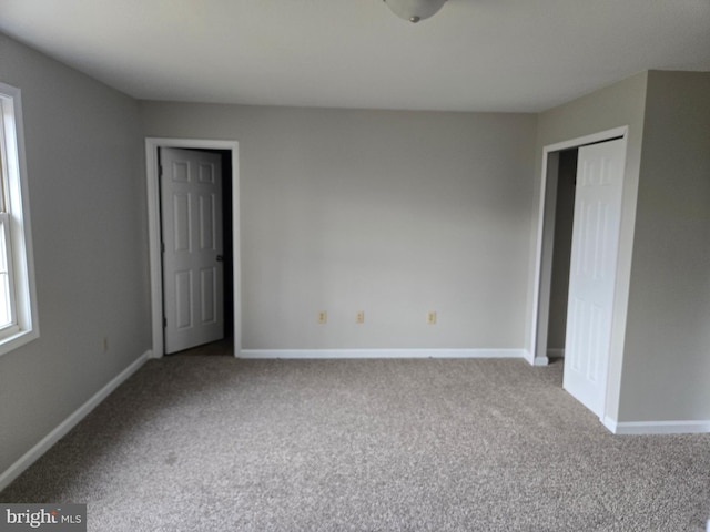 unfurnished bedroom with a closet, carpet flooring, and baseboards