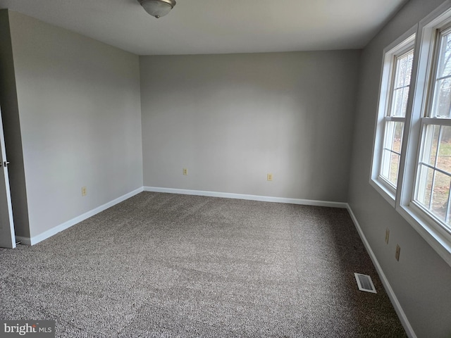 carpeted spare room with baseboards and visible vents