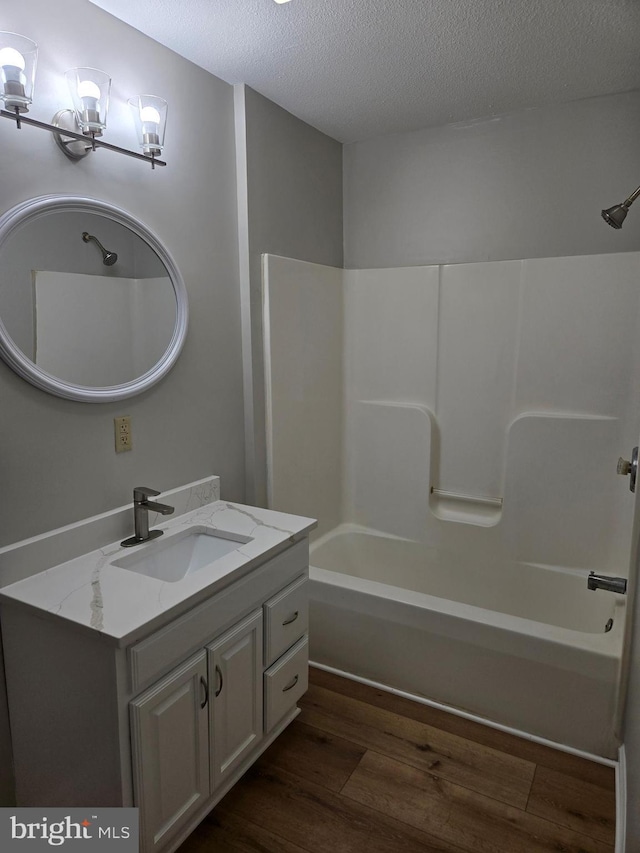 full bathroom with washtub / shower combination, a notable chandelier, a textured ceiling, vanity, and wood finished floors