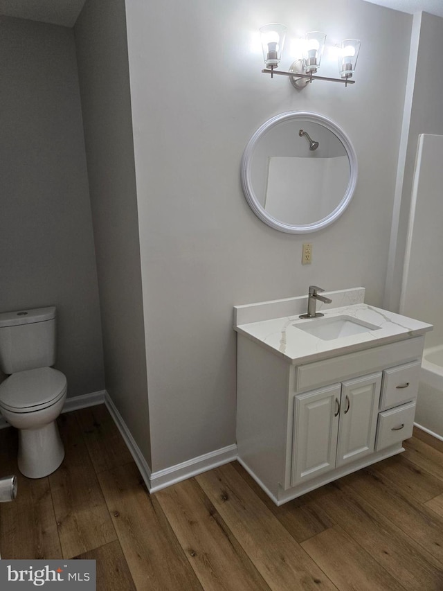 bathroom featuring vanity, a chandelier, toilet, wood finished floors, and baseboards