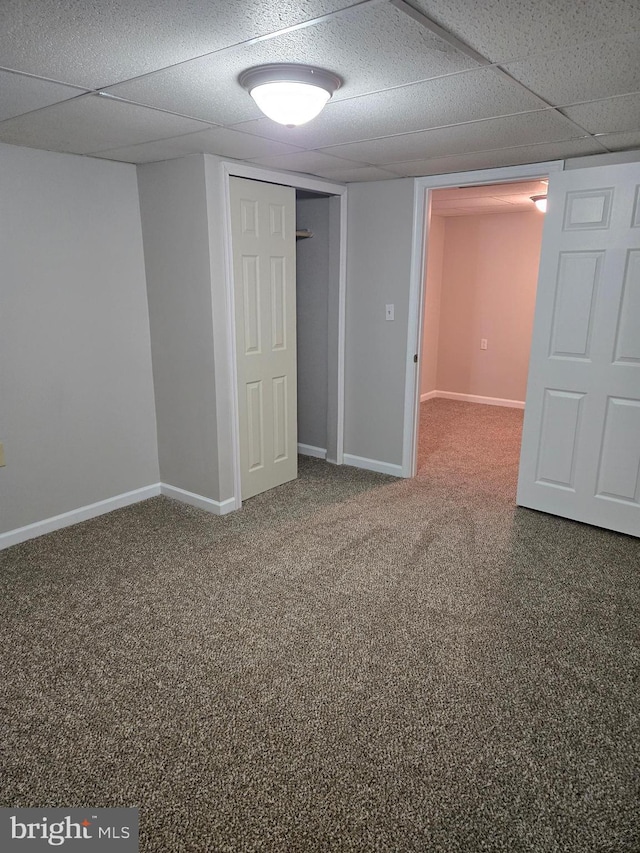 finished basement with a paneled ceiling, carpet flooring, and baseboards