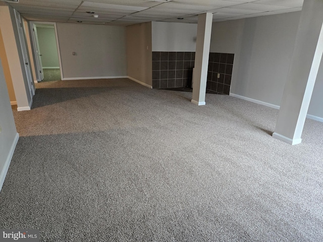 finished below grade area featuring baseboards, a paneled ceiling, and carpet