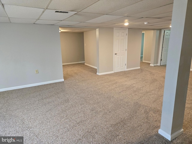 finished below grade area featuring visible vents, baseboards, a drop ceiling, and carpet