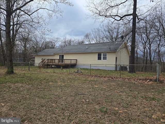 rear view of property featuring fence private yard, a deck, and a lawn