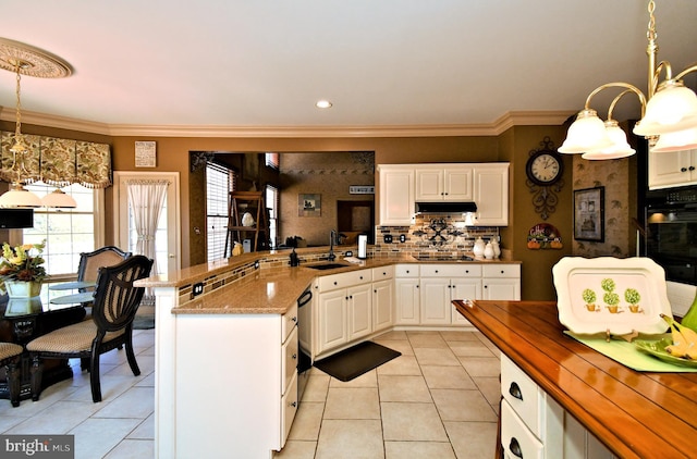 kitchen with pendant lighting, crown molding, light tile patterned floors, white cabinetry, and under cabinet range hood