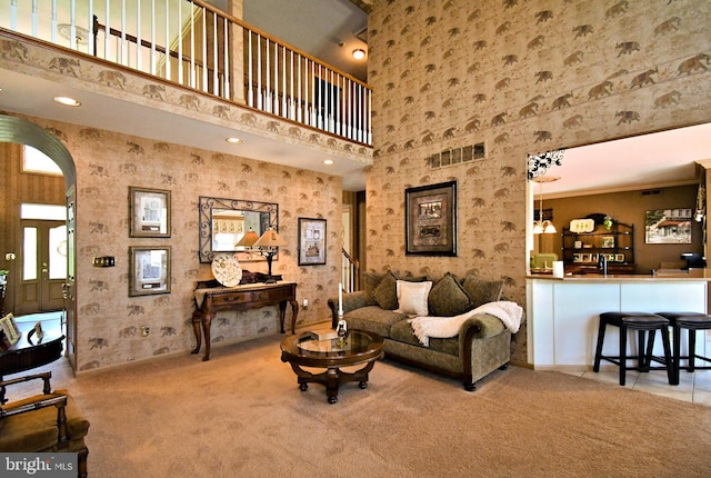living area featuring recessed lighting, a high ceiling, visible vents, arched walkways, and carpet