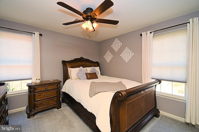 carpeted bedroom with ceiling fan, baseboards, and multiple windows