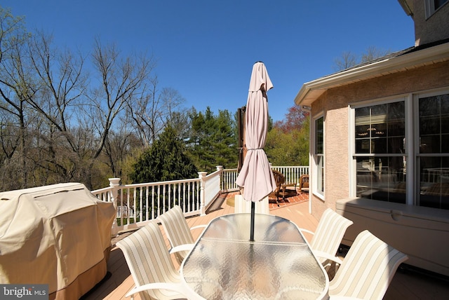 wooden terrace with outdoor dining area and area for grilling