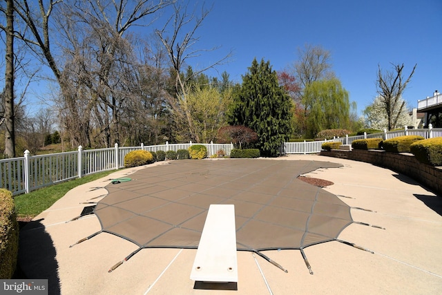 view of swimming pool featuring fence, a patio, and a diving board
