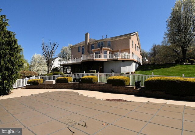 rear view of property featuring a chimney, a patio area, stucco siding, and fence private yard