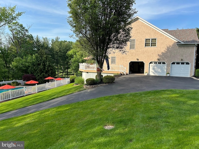 view of home's exterior with aphalt driveway, a yard, fence, and stucco siding