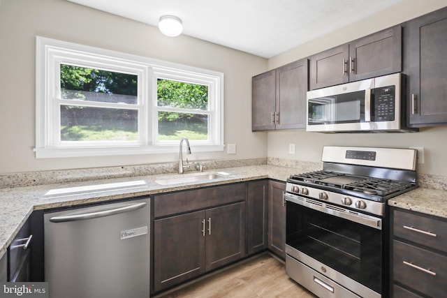 804 Farms River Rd, Front Royal, VA 22630 - kitchen featuring appliances with stainless steel finishes, a sink, dark brown cabinets, light wood-style floors, and light stone counters