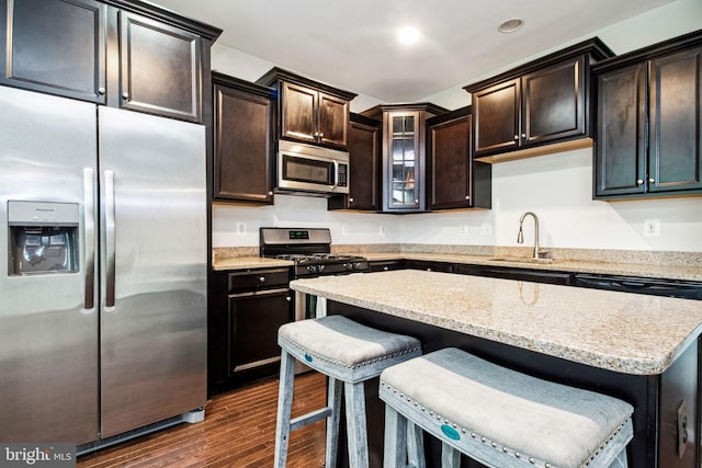 kitchen featuring dark wood-type flooring, a breakfast bar, a center island, a sink, and stainless steel appliances