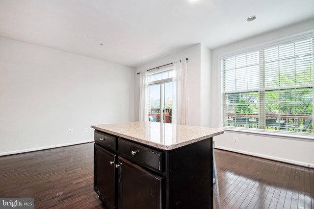 kitchen featuring a kitchen island, baseboards, dark wood-style floors, and a wealth of natural light