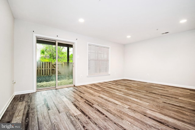 unfurnished room with wood finished floors, baseboards, visible vents, and recessed lighting