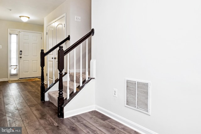 entrance foyer featuring dark wood-style flooring, baseboards, visible vents, and stairs