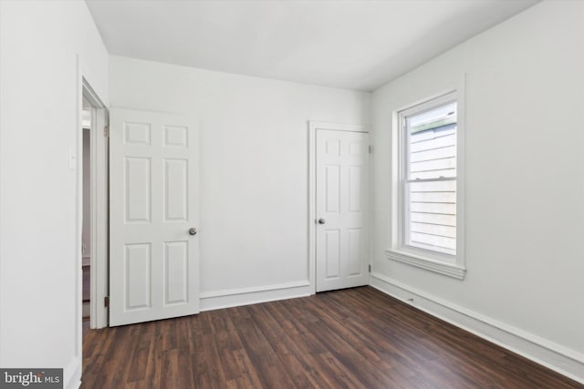 unfurnished bedroom with baseboards and dark wood finished floors