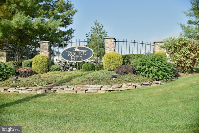 community / neighborhood sign with a yard and fence
