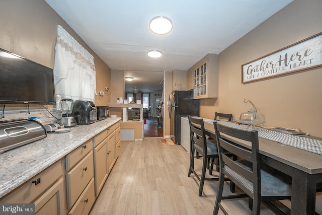 4990 W Thompson St, Philadelphia, PA 19131 - kitchen with light wood-style floors, light stone counters, glass insert cabinets, and black appliances