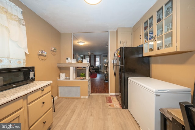 4990 W Thompson St, Philadelphia, PA 19131 - kitchen with baseboards, glass insert cabinets, light countertops, light wood-style floors, and black appliances