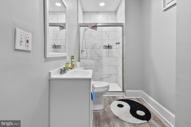 full bath featuring vanity, toilet, wood finished floors, a marble finish shower, and baseboards