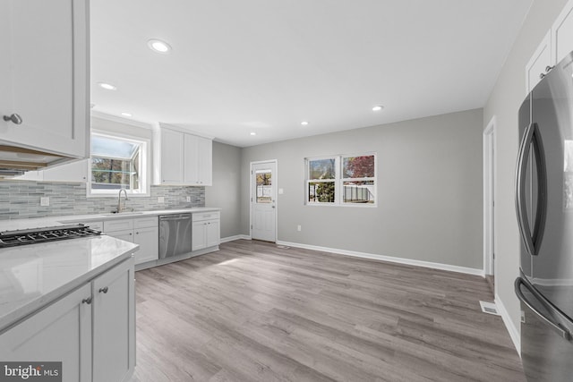 kitchen with white cabinets, backsplash, stainless steel appliances, and baseboards