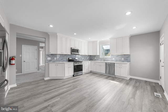 kitchen with light wood-style floors, tasteful backsplash, visible vents, light countertops, and appliances with stainless steel finishes