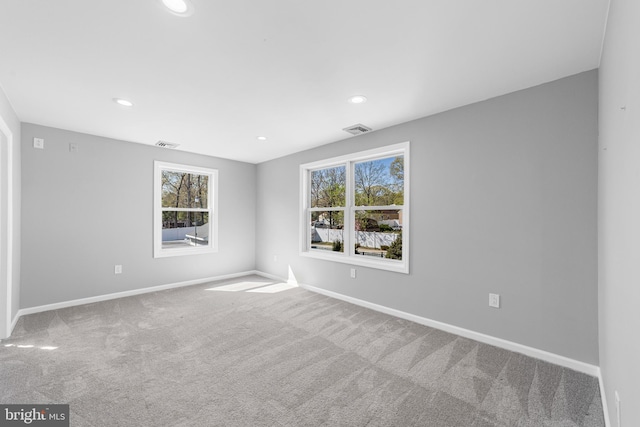 carpeted spare room with baseboards, visible vents, a wealth of natural light, and recessed lighting