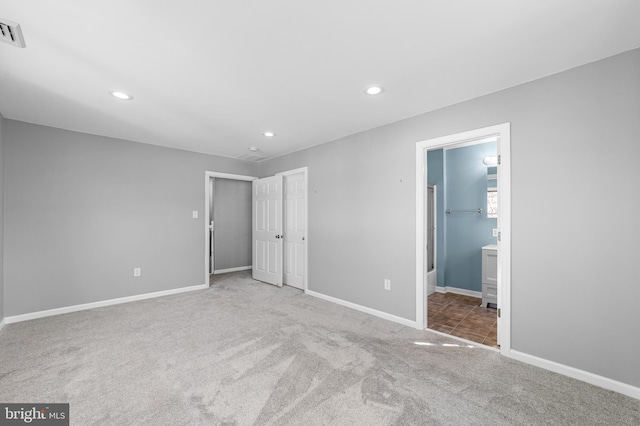 unfurnished bedroom featuring recessed lighting, carpet floors, ensuite bathroom, baseboards, and visible vents