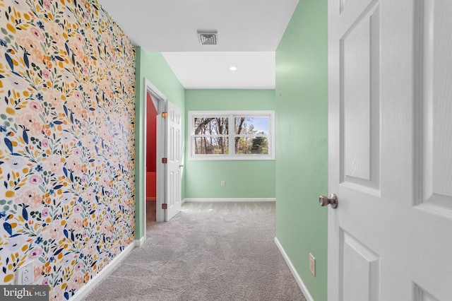 hall with baseboards, visible vents, and carpet