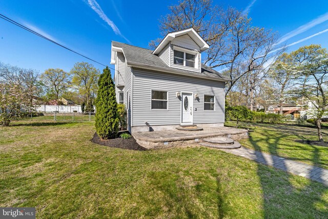 view of front of property with fence, roof with shingles, and a front yard
