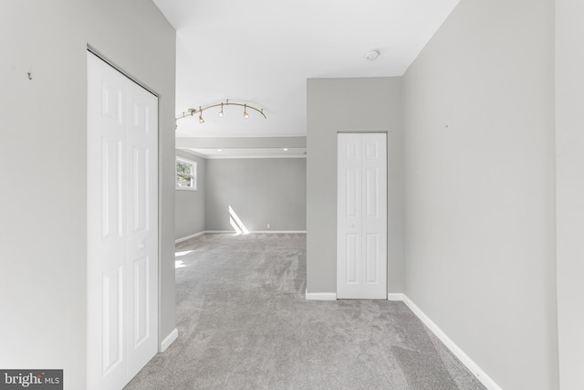 corridor with rail lighting, carpet flooring, and baseboards