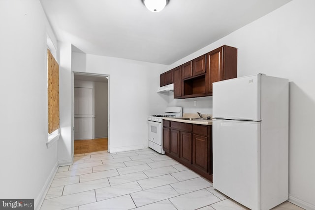 kitchen featuring a sink, light countertops, white appliances, and dark brown cabinets
