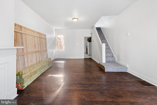 unfurnished living room with stairs, visible vents, baseboards, and wood finished floors