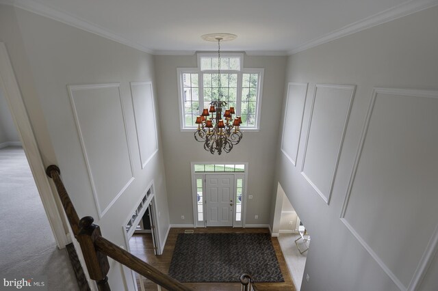 entryway with a chandelier, baseboards, and ornamental molding