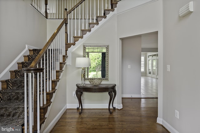 staircase with wood finished floors, baseboards, and a high ceiling