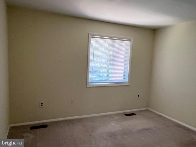 carpeted spare room featuring baseboards and visible vents