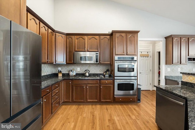 7135 Hills Ln, Warrenton, VA 20187 - kitchen with stainless steel appliances, high vaulted ceiling, light wood finished floors, tasteful backsplash, and dark stone countertops