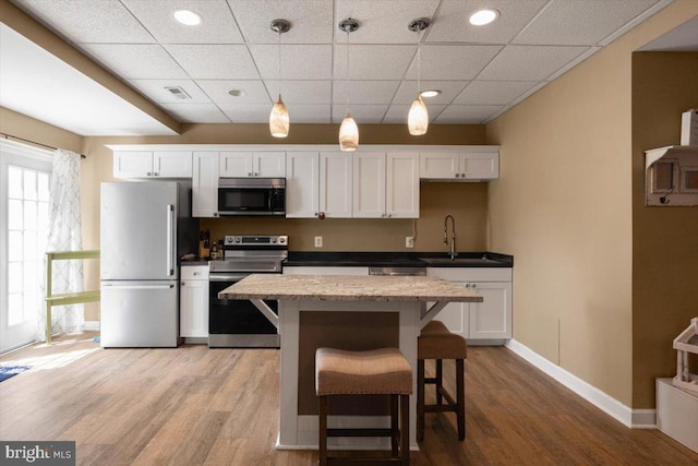 7135 Hills Ln, Warrenton, VA 20187 - kitchen featuring appliances with stainless steel finishes, a sink, light wood-style floors, white cabinets, and a kitchen island
