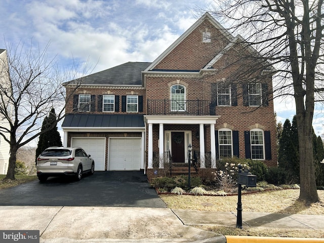 colonial inspired home with brick siding, driveway, roof with shingles, a balcony, and an attached garage