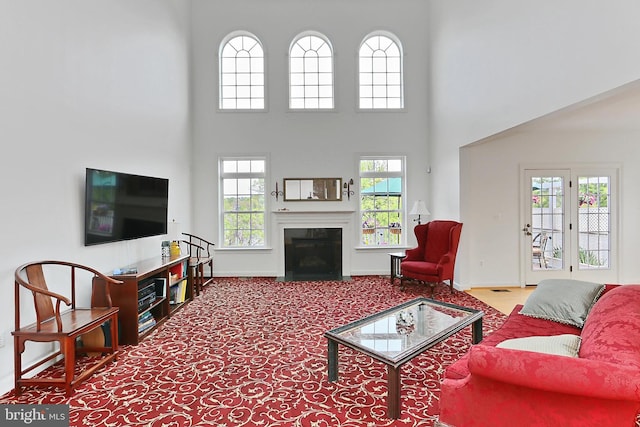 living area with a high ceiling, baseboards, and a fireplace