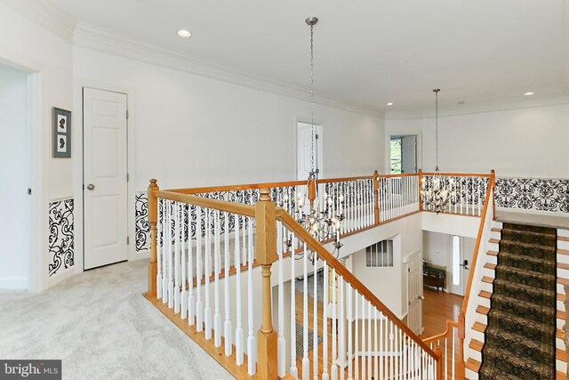 corridor with recessed lighting, carpet floors, ornamental molding, an upstairs landing, and a notable chandelier
