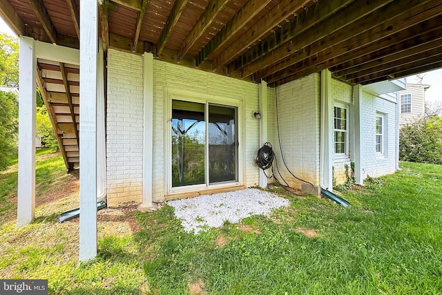 doorway to property featuring a yard and brick siding