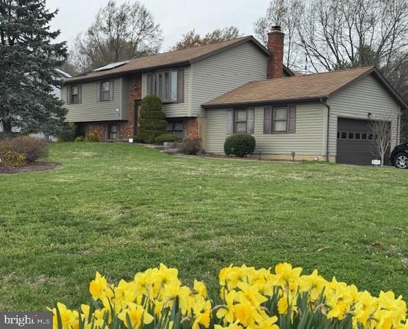 view of front of house with a chimney, a front lawn, and a garage