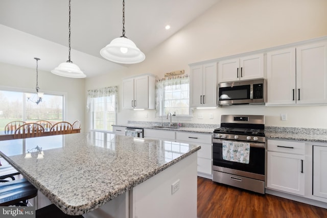 kitchen with a center island, white cabinetry, a kitchen bar, appliances with stainless steel finishes, and a sink