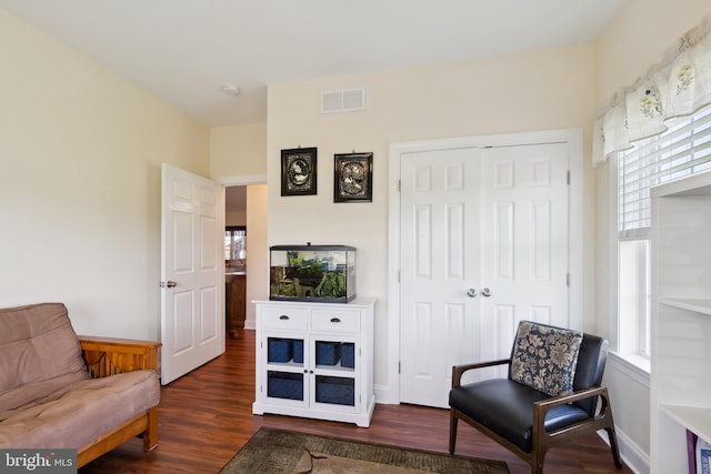 living area with dark wood-type flooring, visible vents, and baseboards