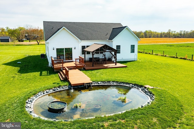 rear view of house featuring a gazebo, a wooden deck, fence, and a lawn
